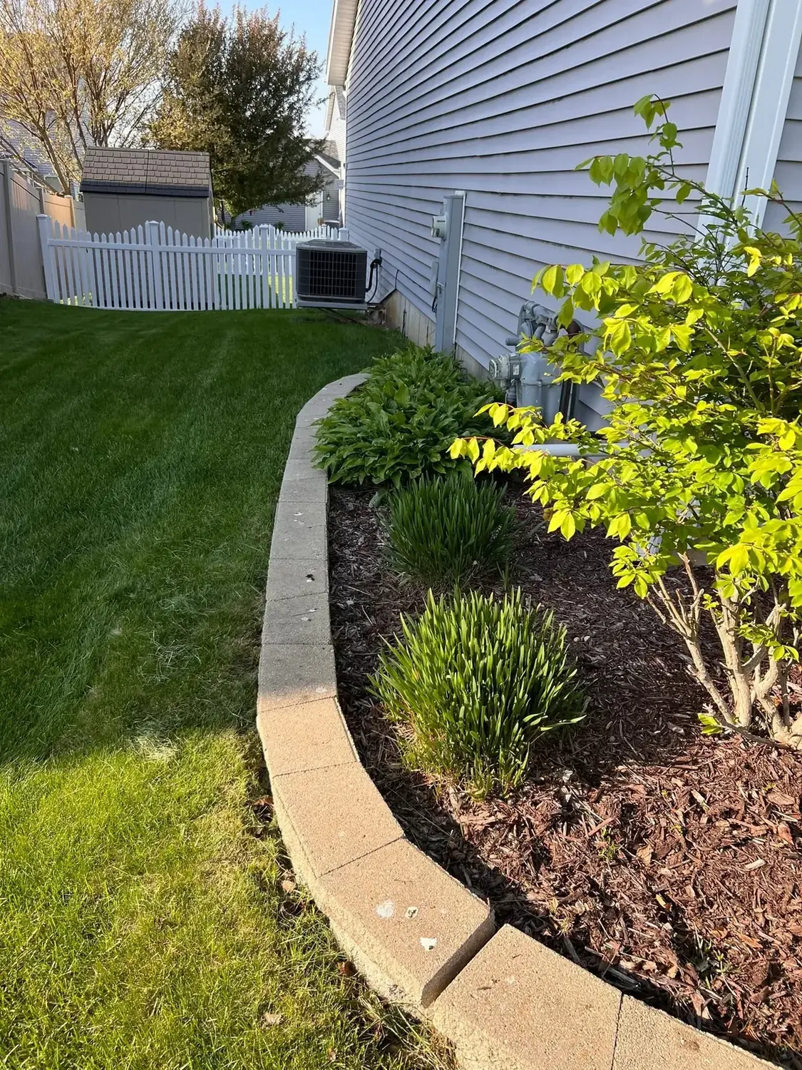 Curved foundation bed with stone edging and fresh mulch