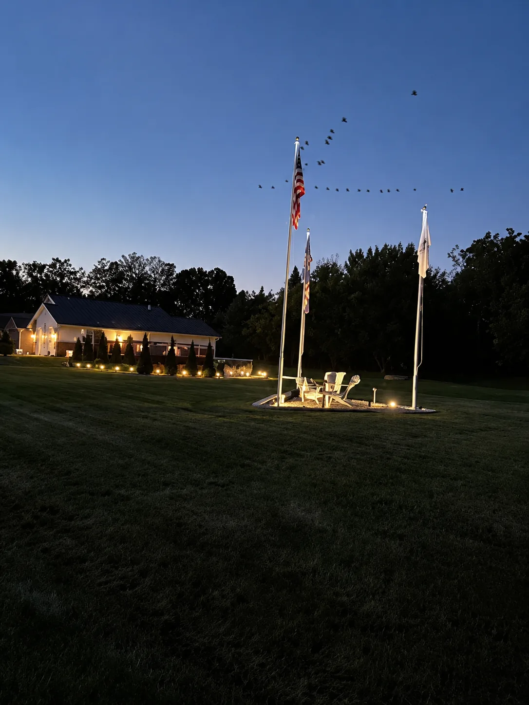 Maintained lawn and illuminated flag display at dusk