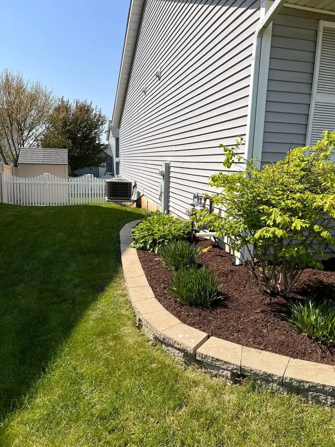 Finished side-yard garden bed with stone border and mulch